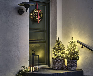 Adventni venec na vratih in umetni drevesi z lučkami