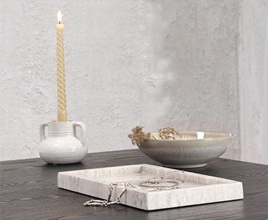 Svečnik, sveča, pladenj in posoda na mizici