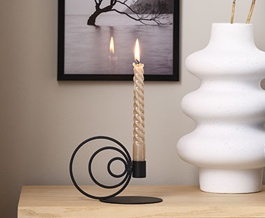 Svečnik v črni barvi s svečo ob beli vazi
