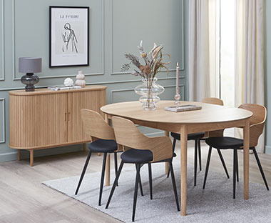Ovalna jedilna miza z lesenimi stoli z oblazinjenim sedežem