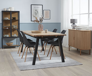 Jedilniški stoli v črni barvi z lesenimi nogami in jedilna miza z vitrino v jedilnici