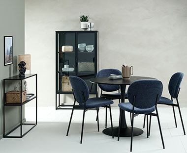 Jedilnica v črni barvi in modrimi stoli z okroglo jedilniško mizo,  vitrino in konzolno mizo