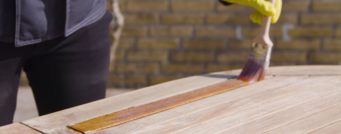 Oseba, ki prikazuje, kako vzdrževati leseno vrtno pohištvo