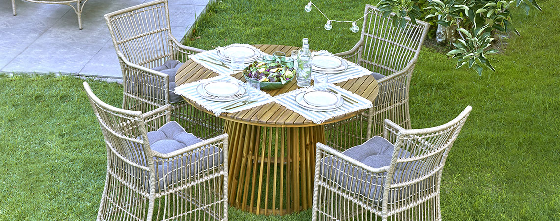 Okrogla vrtna miza s štirimi vrtnimi stoli na travi