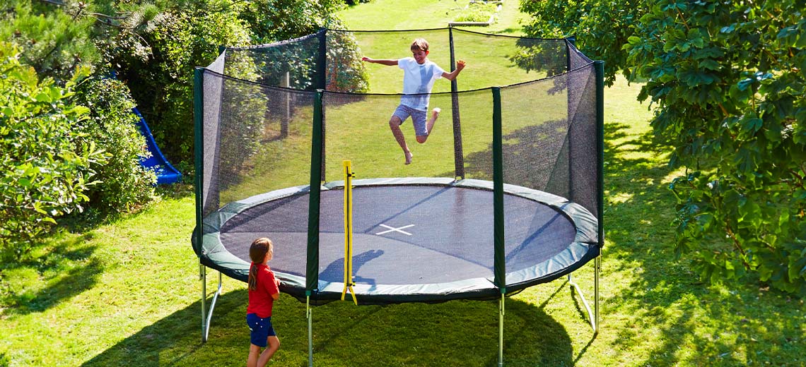 Otroci se igrajo na velikem trampolinu na vrtu