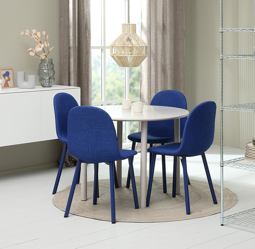 Jedilniški stol v obliki školjke v kobalt modri barvi ob okrogli jedilniški mizi