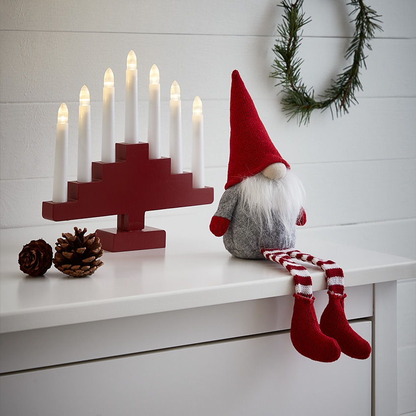 Božični škrat z veliko belo brado, koničasto rdečo kapo in dolgimi nogavicami