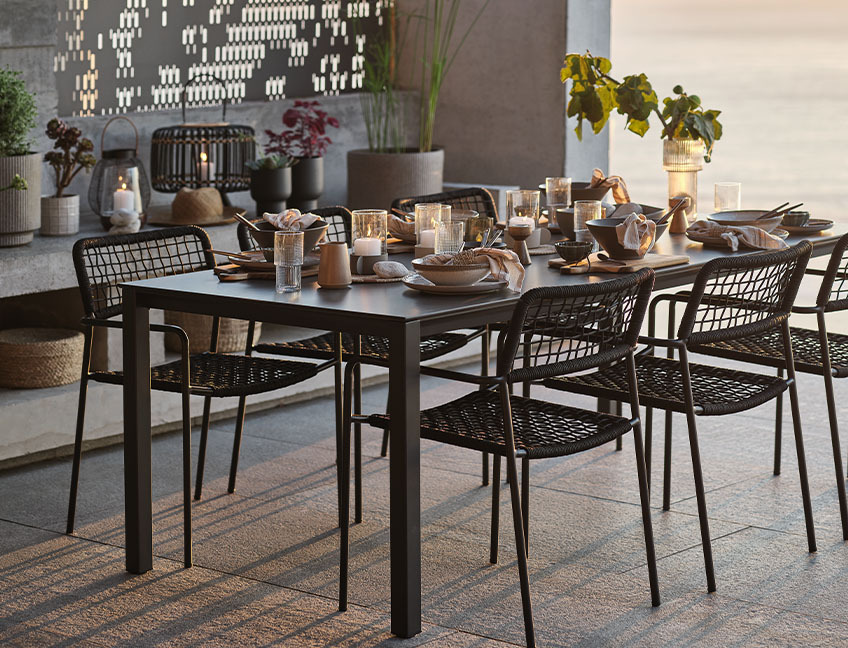 Vrtna miza in vrtni stoli z mizo za večerjo na terasi ob sončnem zahodu