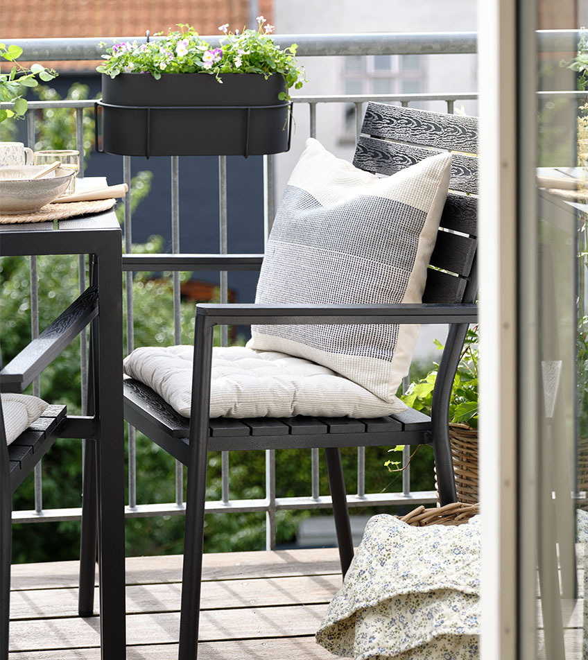 Črn nakladljiv vrtni stol z blazinami na balkonu