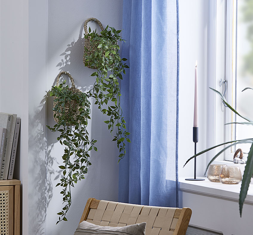 Dve pleteni košari z umetnim rastlinjem na steni dnevne sobe