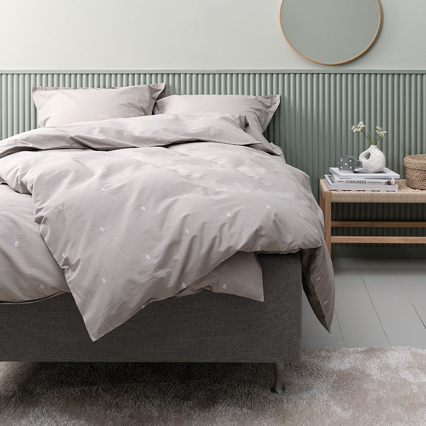 Bombažna posteljnina v svetlo sivi barvi vključno s prevleko za vzglavnik na postelji v spalnici