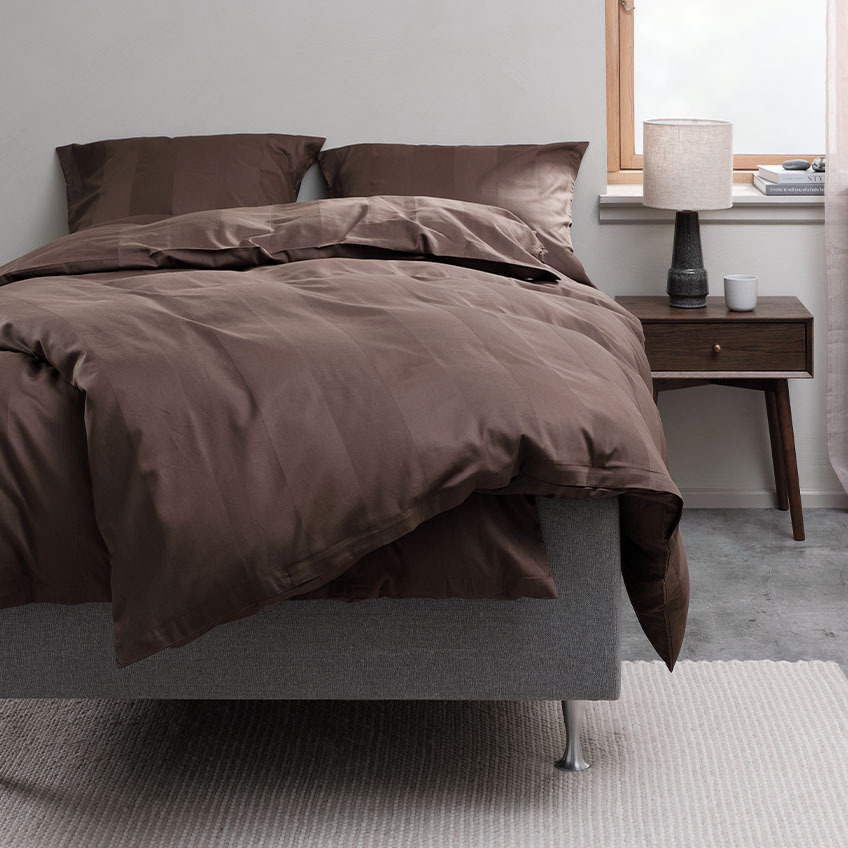 Spalnica in postelja s posteljnino v čokoladno rjavi barvi