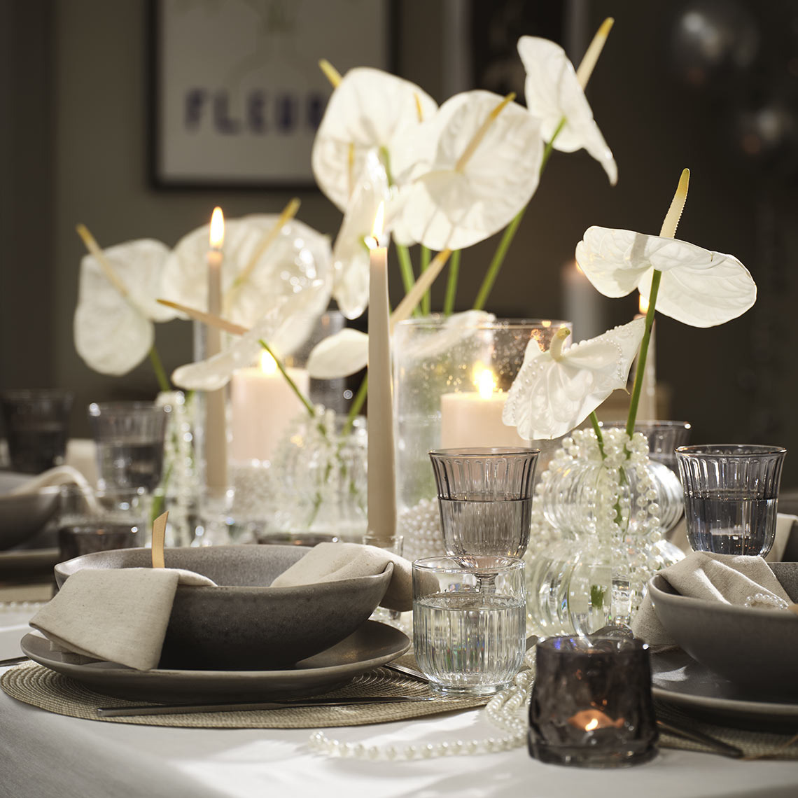 Postavitev jedilne mize s skledami, krožniki, kozarci in svečniki