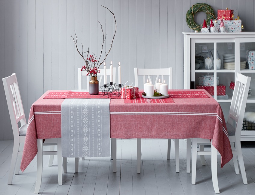 Jedilna miza s stoli okrašena za božično večerjo z rdečim prtom in belimi svečami