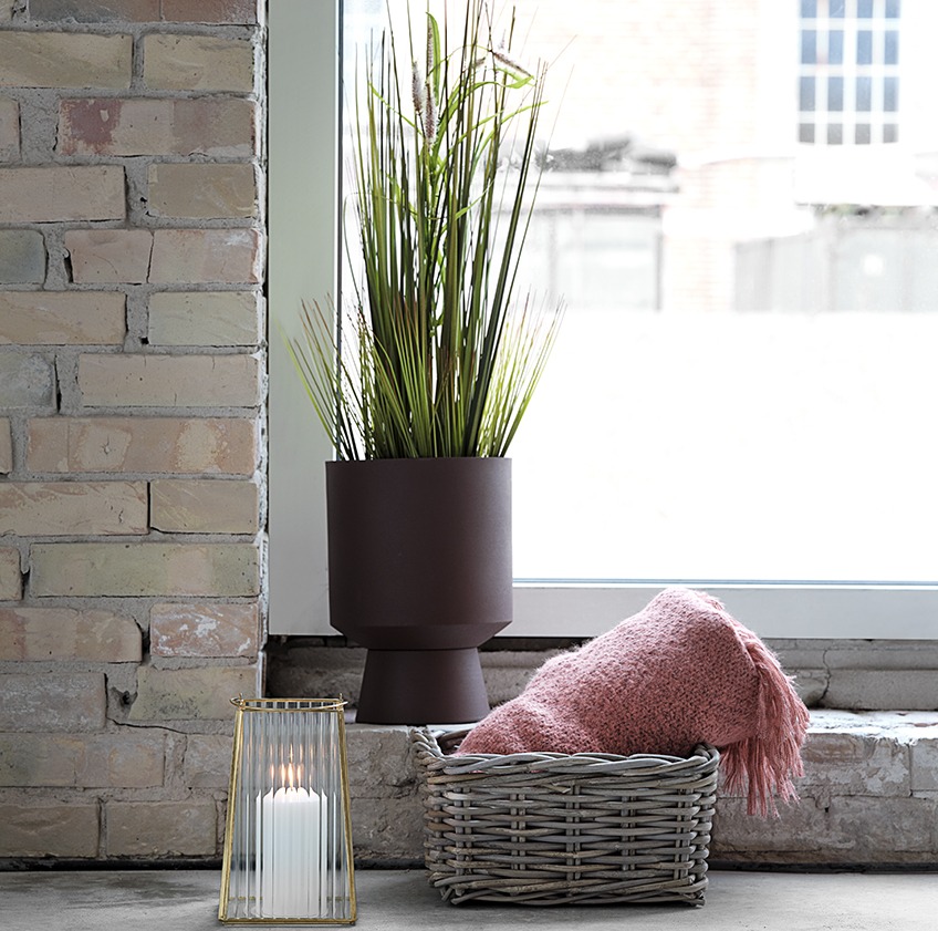 Svetlični lonček z umetno rastlino, lanterna in košara z odejo ob oknu