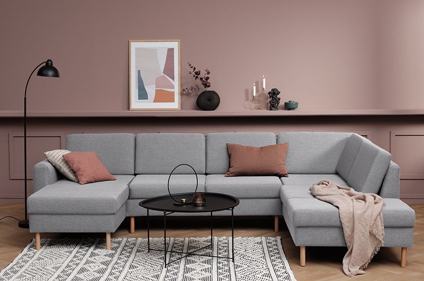 Večji siv kavč z blazinami in odejo v moderni dnevni sobi 