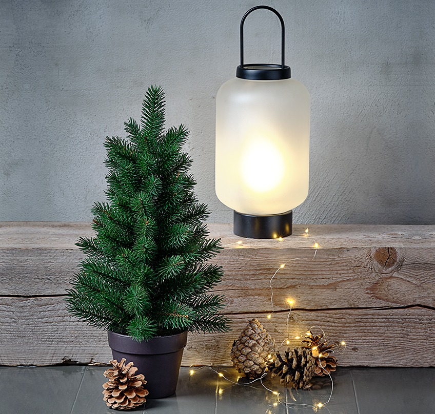 Umetno božično drevo, steklena lanterna, ki izgleda zaledenela, in veriga novoletnih lučka