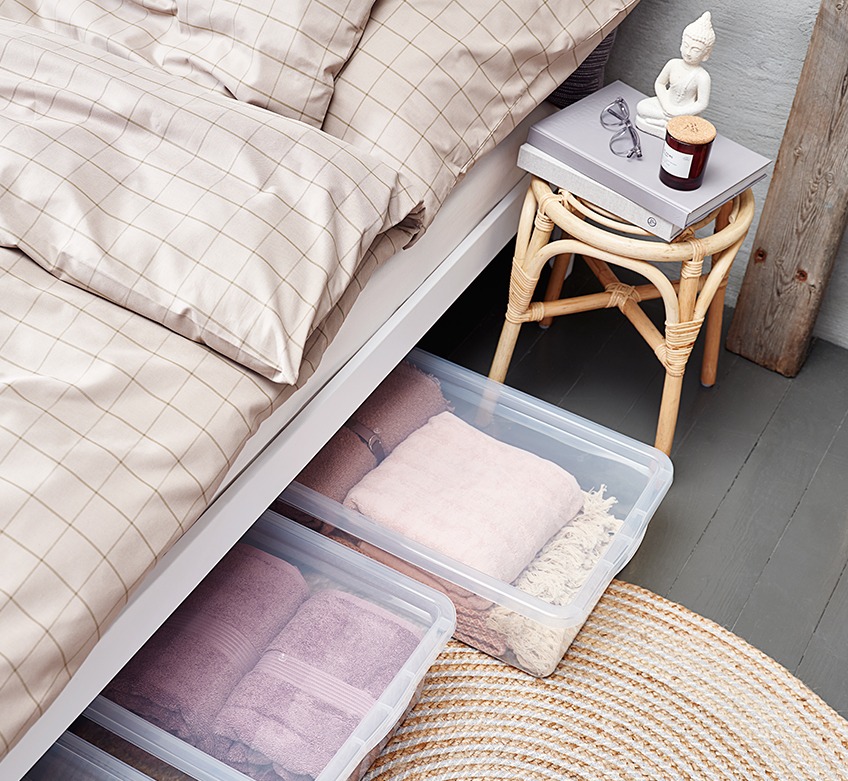 Postelja s posteljnino in škatle pod posteljo