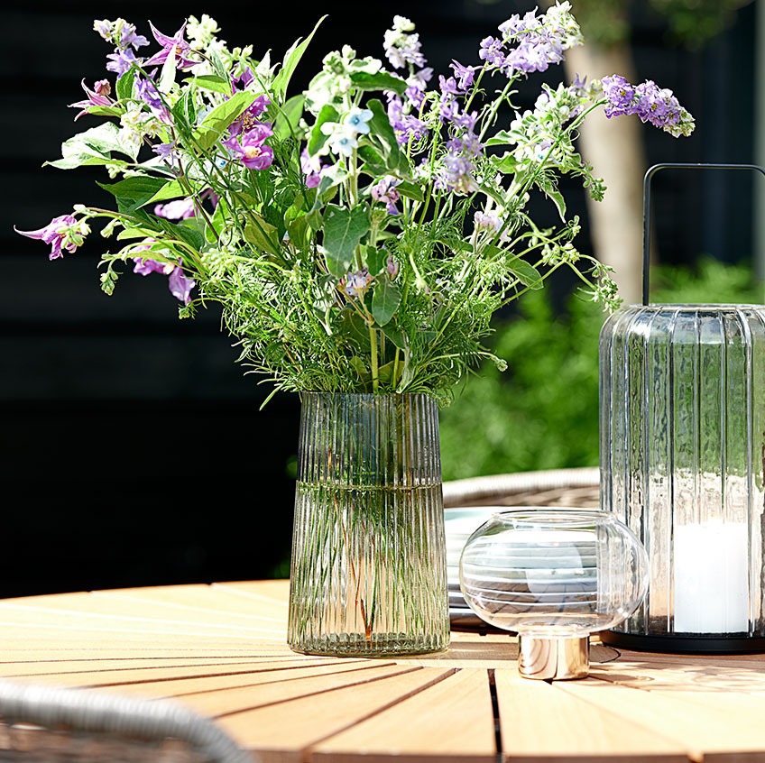 Steklena vaza in lanterna na vrtni mizi iz tikovine