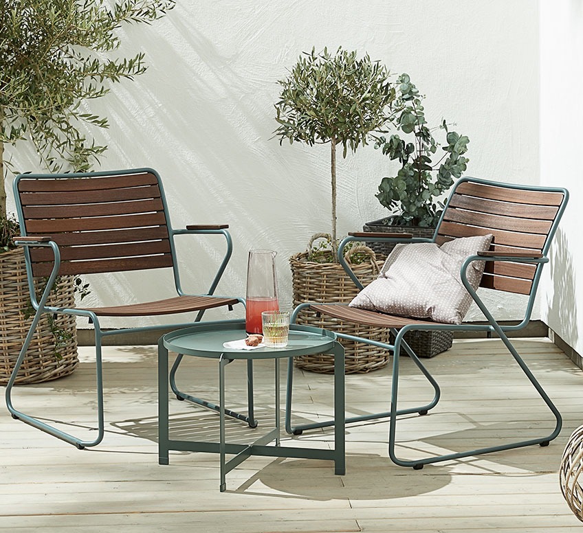 Dva lesena vrtna lounge stola z zelenim kovinskim okvirjem in mala lounge mizica na terasi