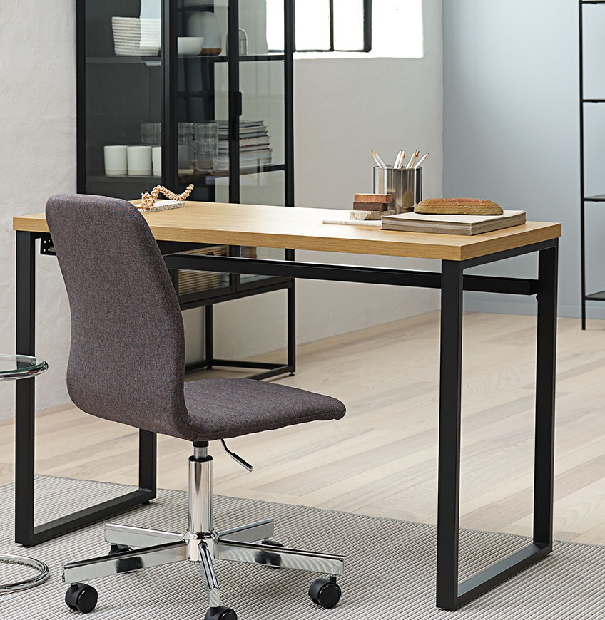 Pisalna miza s črnimi kovinskimi nogami in siv pisarniški stol
