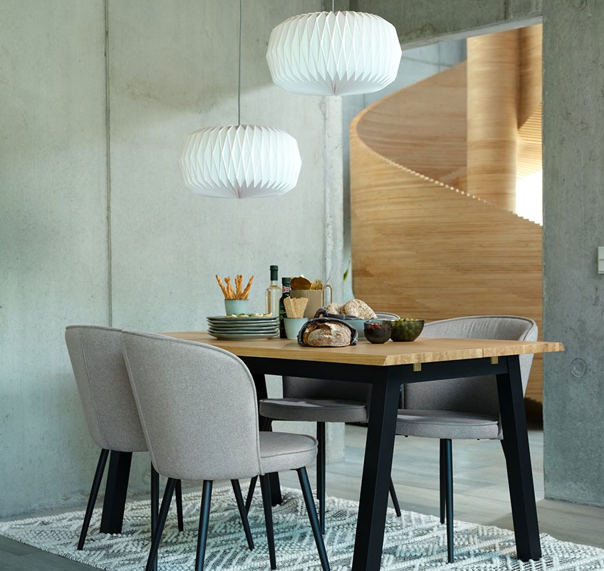 Jedilna miza s štirimi jedilniškimi stoli v sivi barvi s čnimi nogami in dvema visečima svetilkama