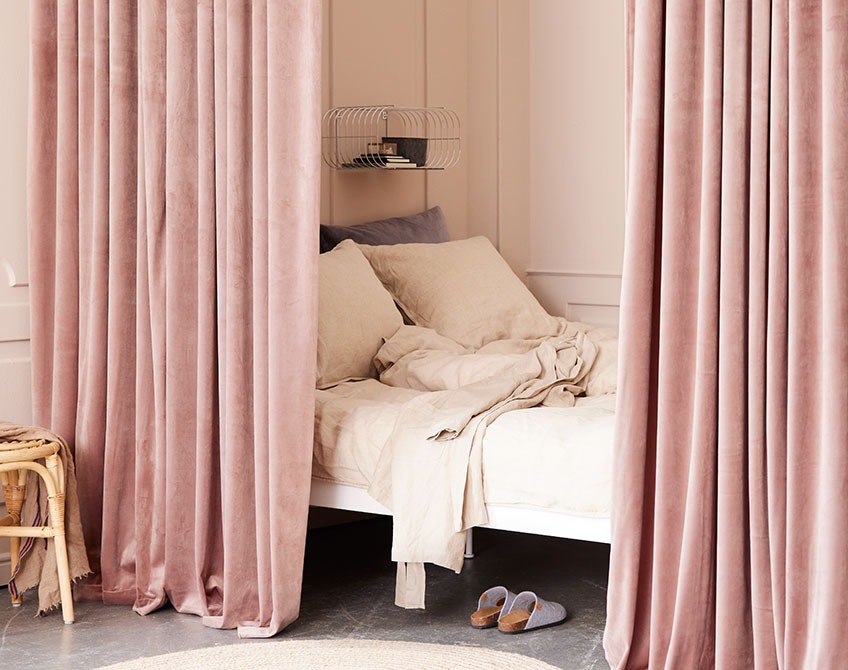 Zavese v roza barvi, ki ločujejo spalni del od dnevne sobe 