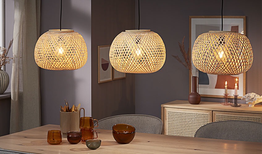 Tri viseče svetilke iz bambusa nad jedilno mizo
