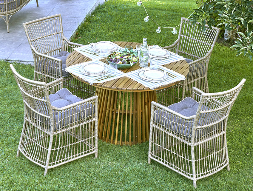 Okrogla vrtna miza s podstavkom in štirimi vrtnimi stoli na travi 
