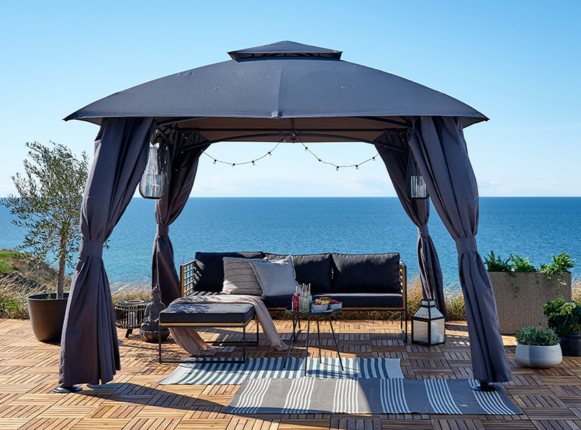 Siv paviljon z lounge vrtnim kompletom in dekoracijami ob morju