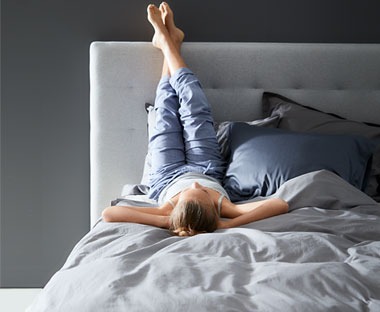 Ženska leži na prešiti odeji na udobni postelji