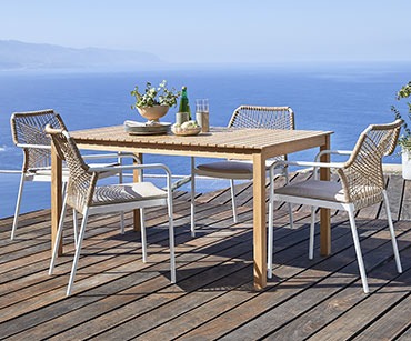 Lesena vrtna miza z modernimi stoli na terasi na morju